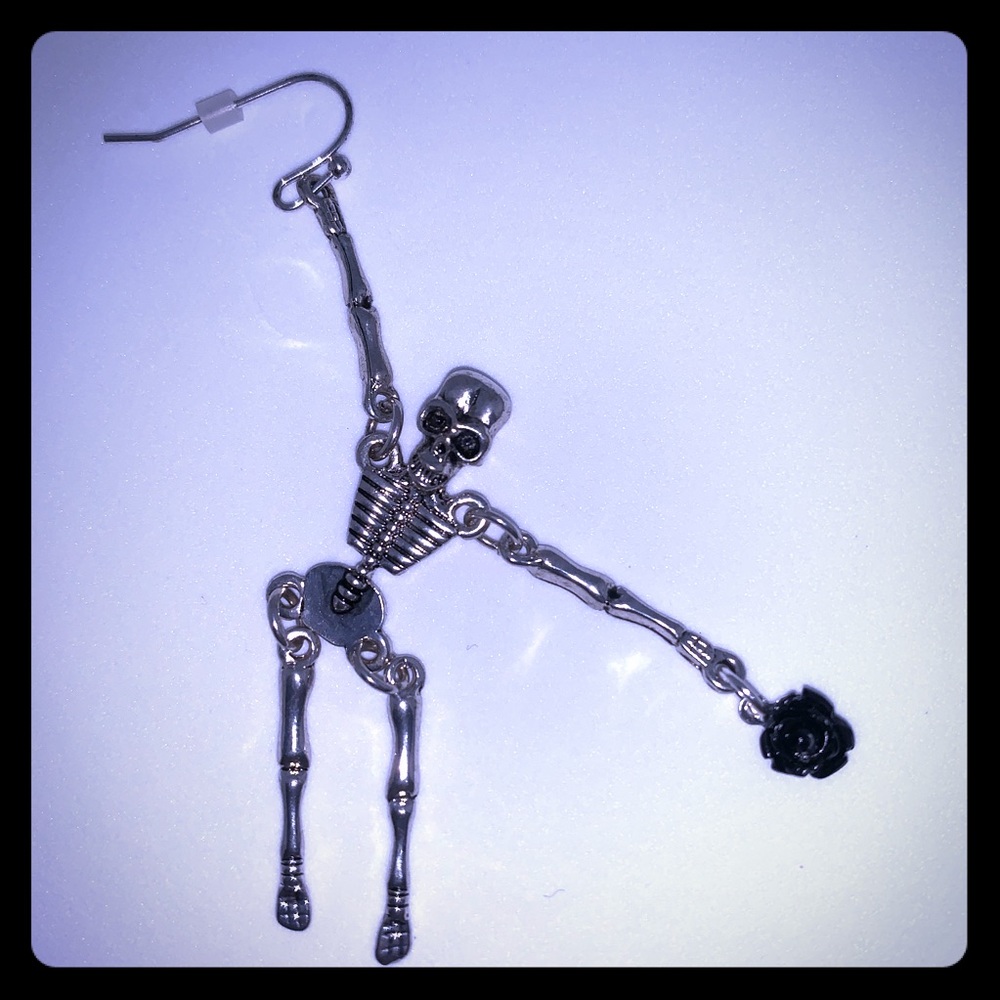 Skeleton dangle earring holding a black rose